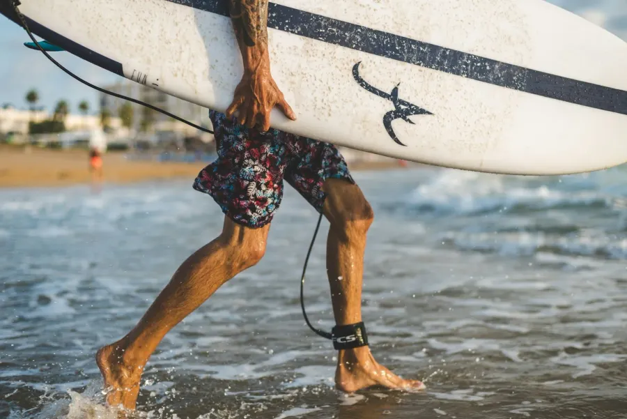 Surfer carrying a board out of the ocean