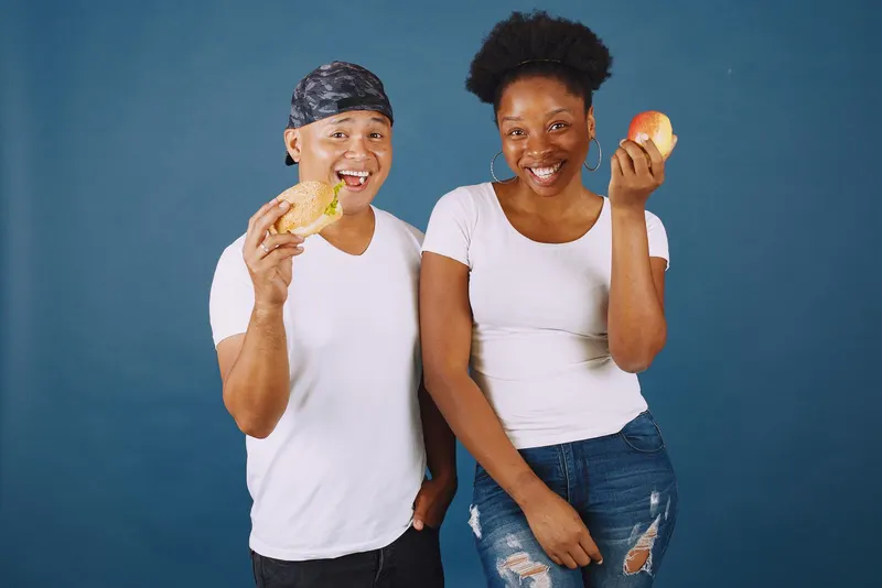 Two friends sharing a snack on a blue backdrop